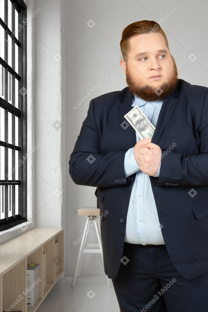A man in a suit and tie hiding money bill in his jacket