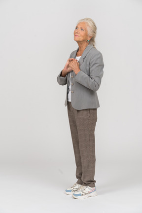 Vista lateral de una anciana feliz en traje mirando hacia arriba