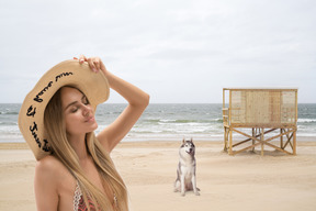 A woman in a bikini on the beach with a husky dog