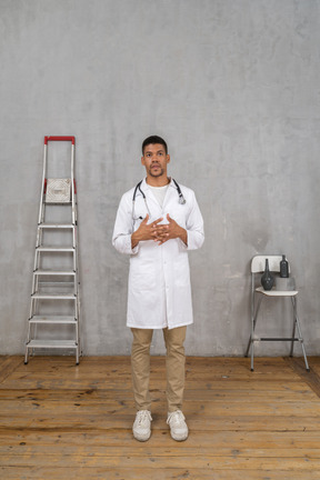 Front view of a young doctor standing in a room with ladder and chair