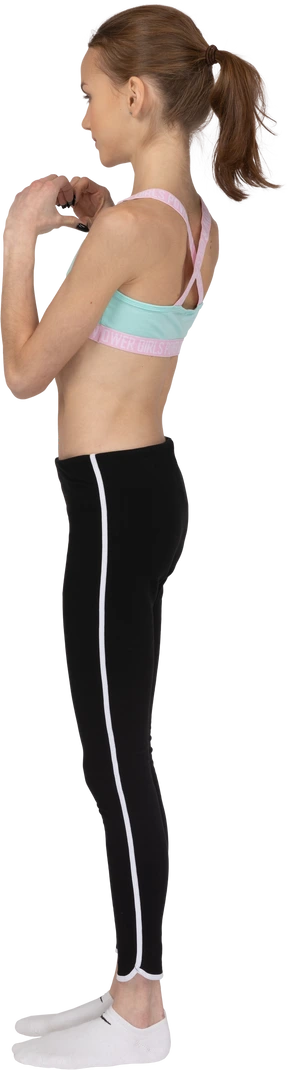 Three-quarter back view of a teen girl in sportswear showing a heart gesture