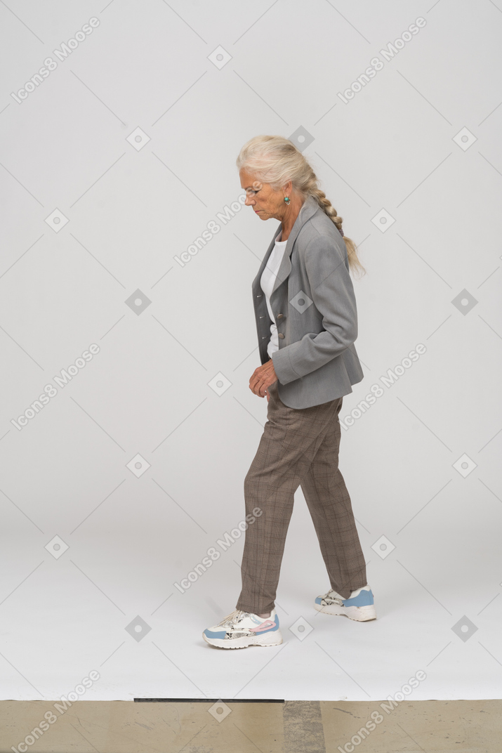 一位穿着西装的老太太走路的侧视图