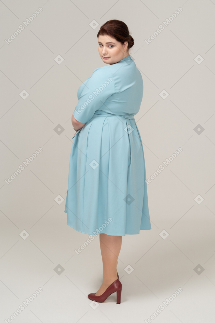 Вид сбоку на женщину в голубом платье, смотрящую вниз