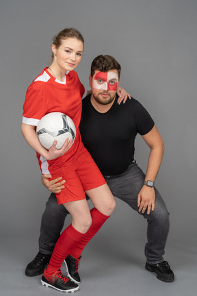 Front view of a male football fan embracing female soccer player