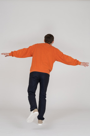 Junger mann im orange sweatshirt springen