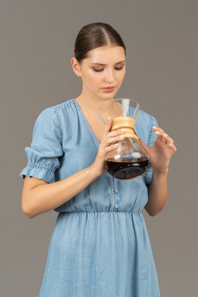 Vista frontal de uma jovem de vestido azul segurando uma jarra de vinho