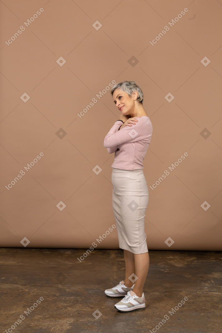 Side view of a happy woman in casual clothes hugging herself