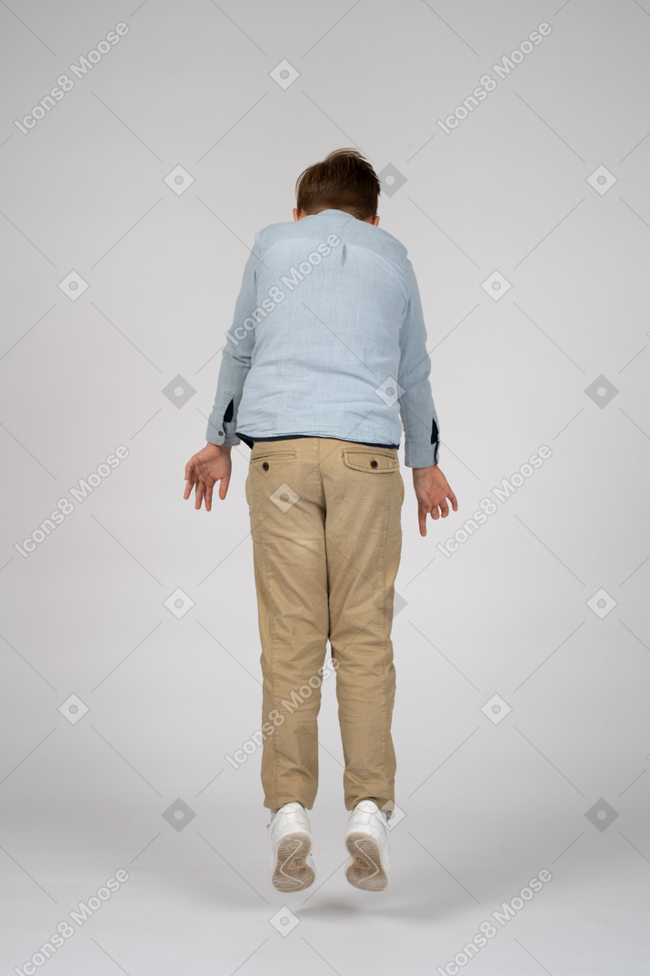 Back view of a boy in a blue shirt jumping