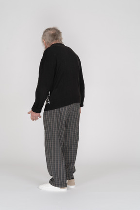 Elderly man standing with his back facing the camera