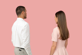 Good looking couple standing against pink background