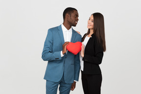 Beautiful interracial couple holding a toy heart together