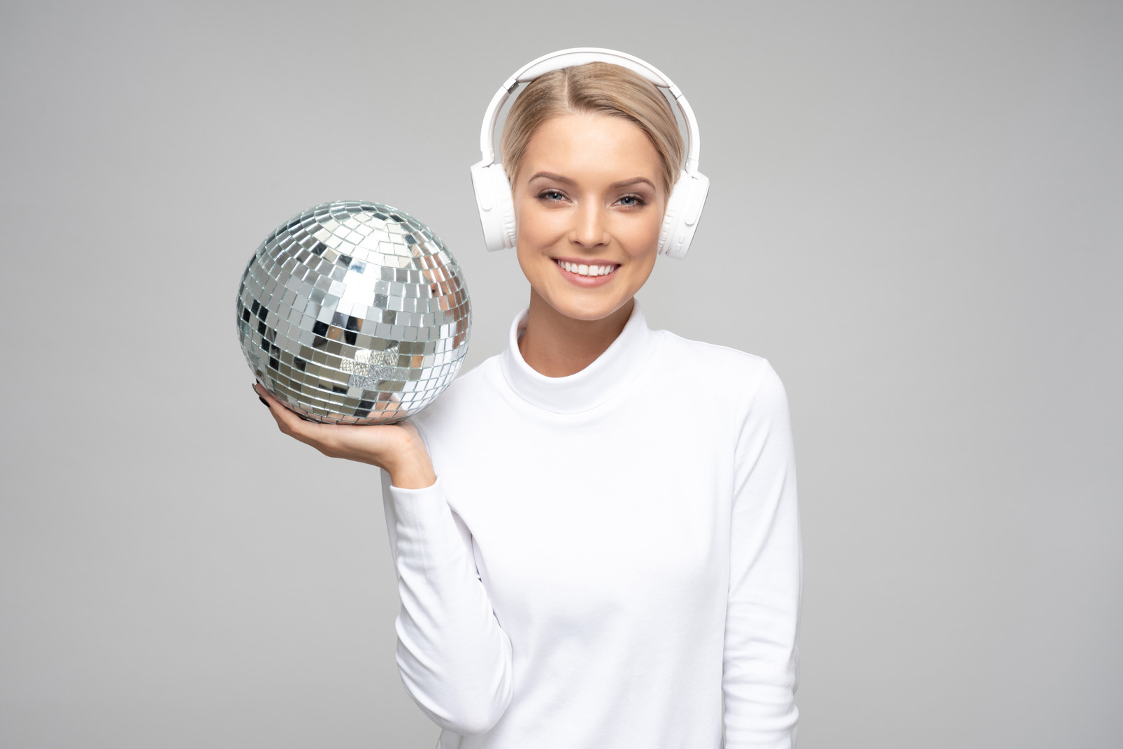 Young woman in headphones holding a disco ball