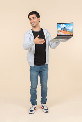 Giovane uomo caucasico che presenta computer portatile