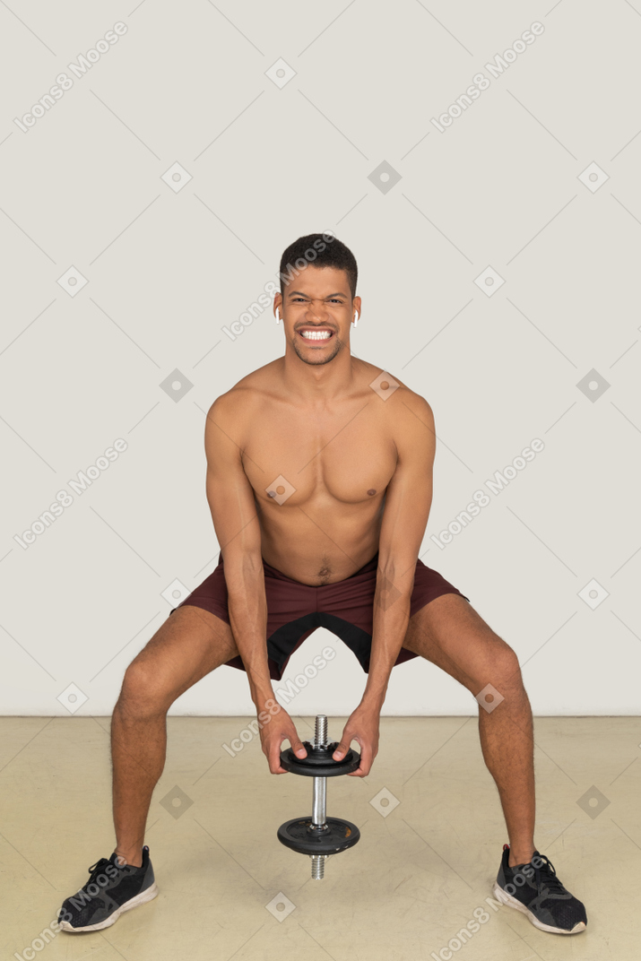 Hombre atlético apretando los dientes mientras levanta pesas