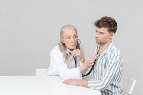 Vieille femme médecin examine un patient avec un stéthoscope