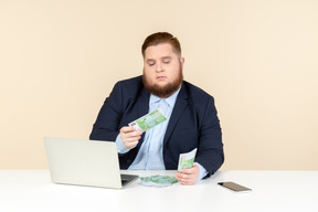 Giovane uomo in sovrappeso assicurandosi che le fatture in denaro siano vere