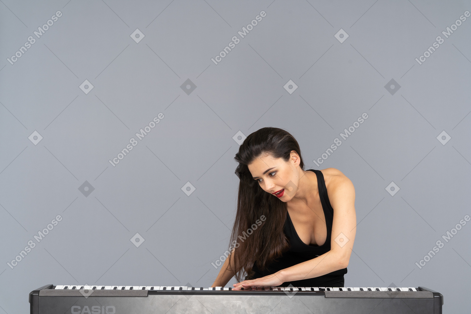 Front view of a young lady in black dress putting her hand on keyboard and leaning aside