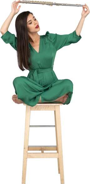 Full-length of a young lady holding her clarinet over head while sitting on a wooden chair