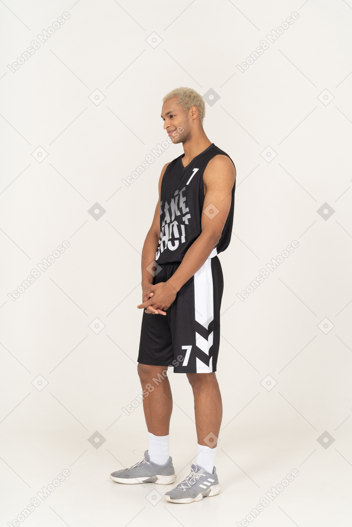 一个害羞的年轻男篮球运动员手牵手的四分之三视图