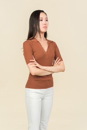 Serious looking young asian woman standing with hands crossed