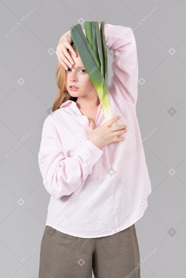 Jeune femme tenant oignon poireau