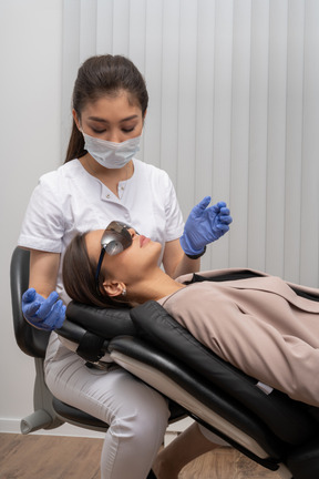 Zahnärztin in maske und latexhandschuhen untersucht ihre patientin