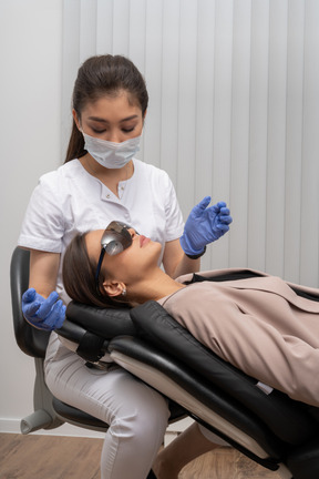 Dentista en máscara y guantes de látex examinando a su paciente