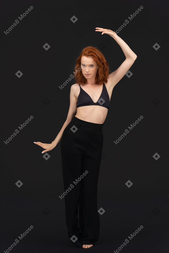A frontal view of the cute young woman dancing on the black background