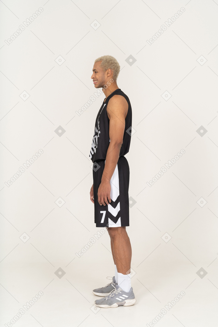 Vista laterale di un giovane giocatore di basket maschio confuso che stringe i denti