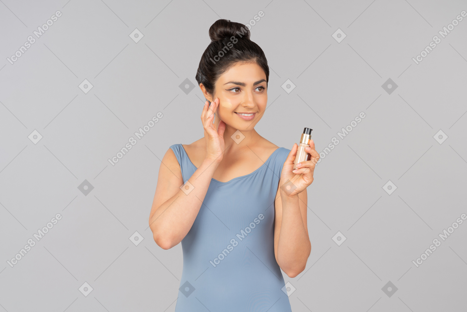 Young indian woman with tonal foundation on her face holding tonal foundation bottle
