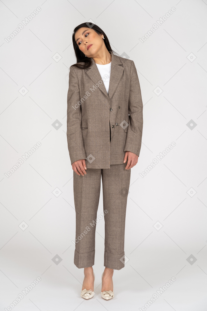 Front view of a young lady in brown business suit tilting head while looking down