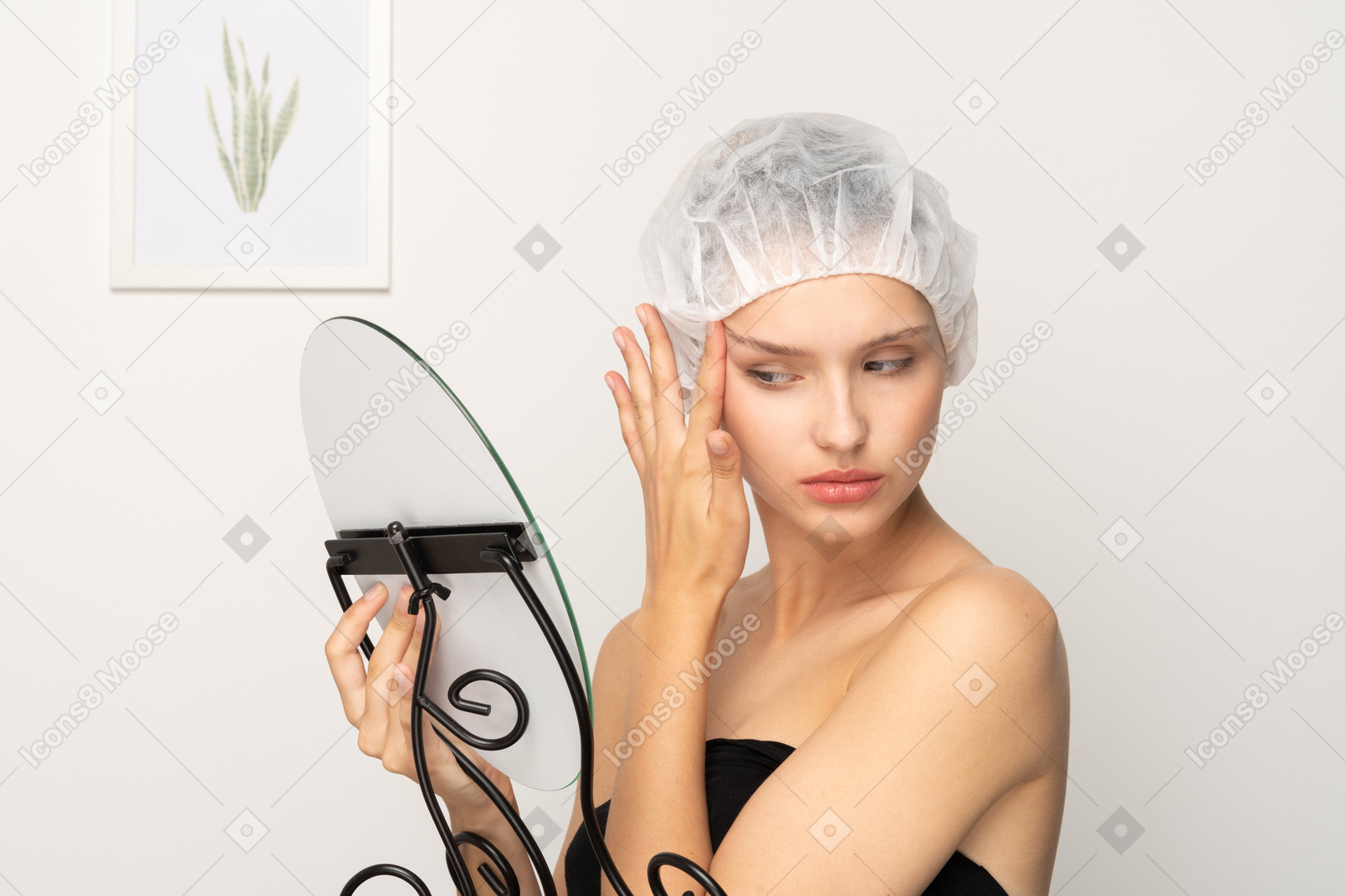 鏡を見ながら顔の肌を引き締める若い女性