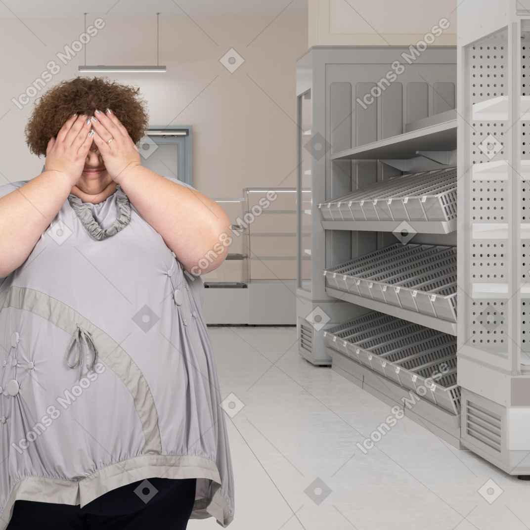 A woman covering her eyes in an empty supermarket