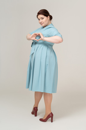 Side view of a woman in blue dress showing heart gesture