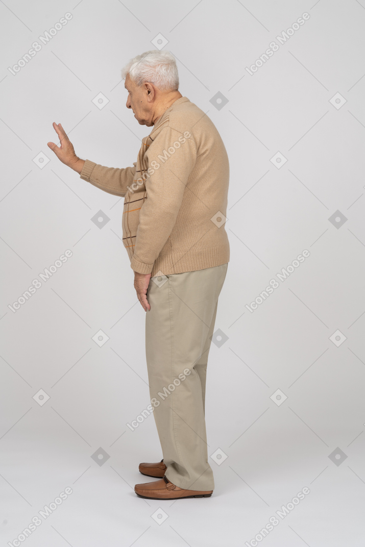 Vista laterale di un uomo anziano in abiti casual che mostra il gesto di arresto