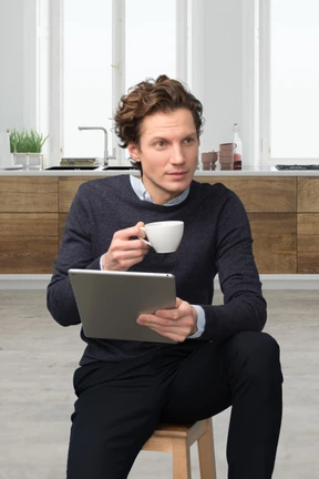 A man sitting on a stool holding a cup of coffee