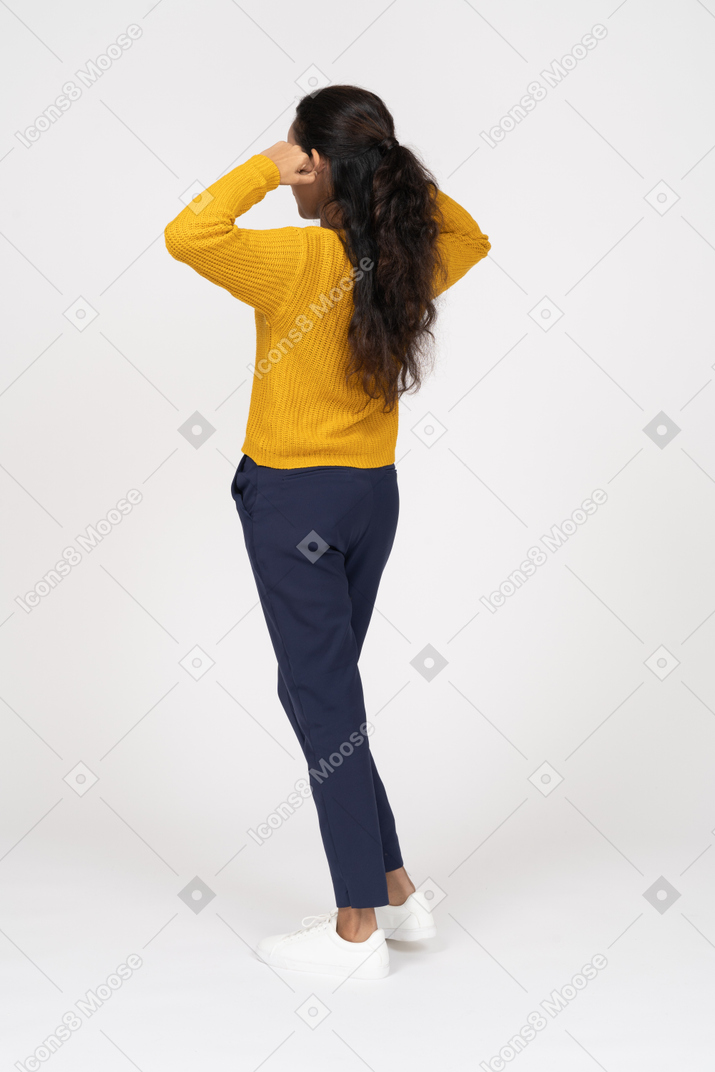 Rear view of a girl in casual clothes touching ears