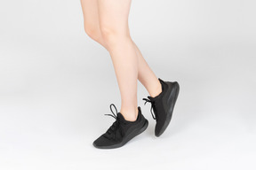 Gambe femminili in scarpe da ginnastica nere