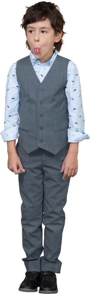 Front view of a cute boy in suit showing tongue