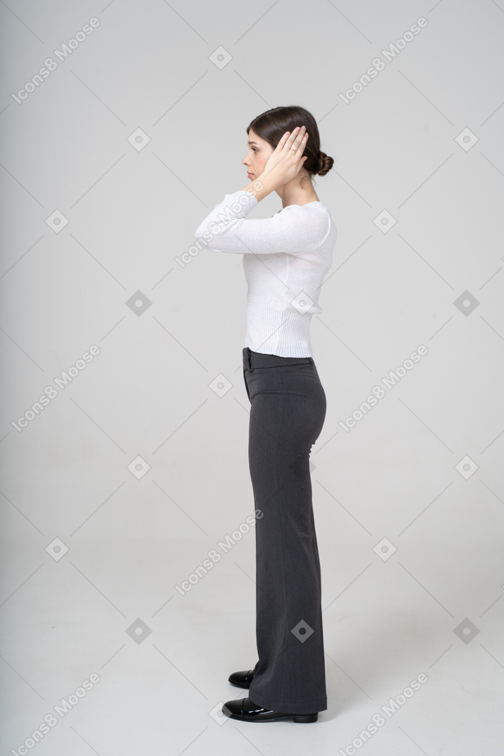 Vista laterale di una donna in abiti casual da lavoro che copre le orecchie con le mani