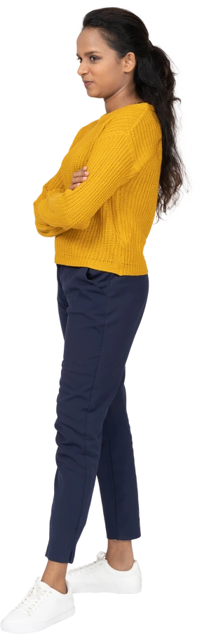 Side view of a girl in casual clothes posing with crossed arms and making faces