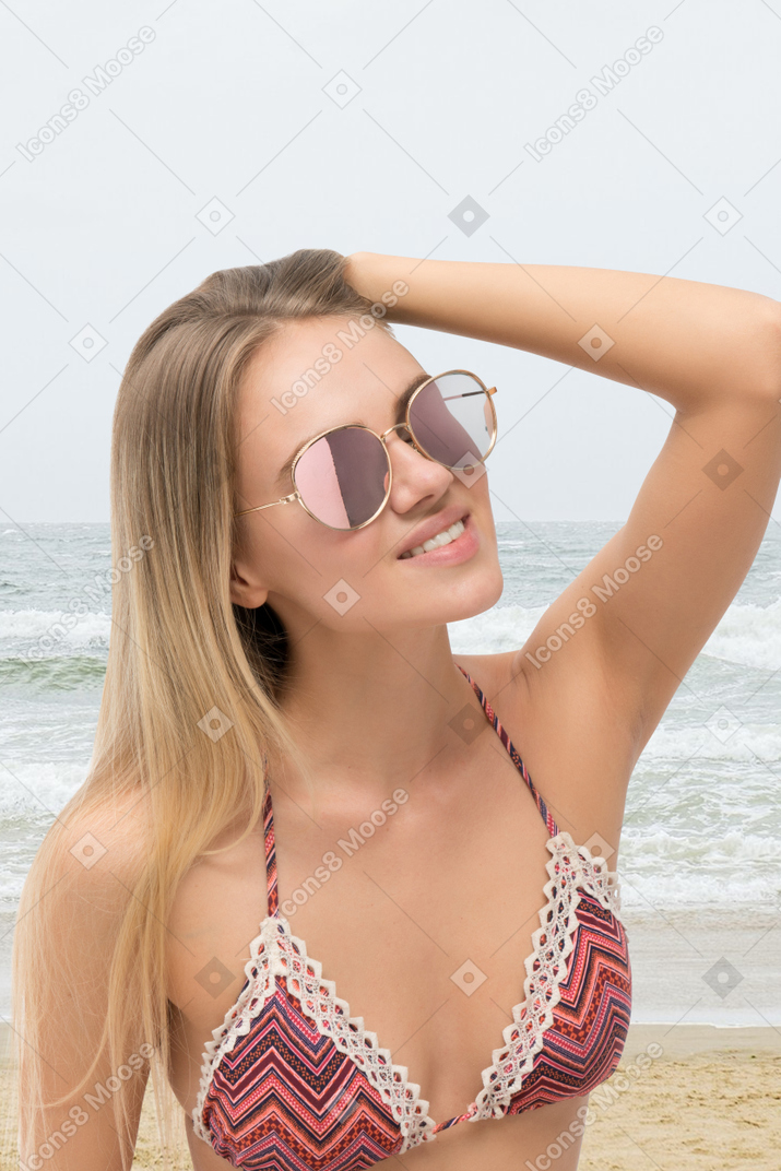 A woman wearing a bikini and sunglasses on the beach