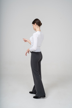 Vista lateral, de, un, mujer joven, en, pantalón negro, y, blusa blanca, señalar con un dedo