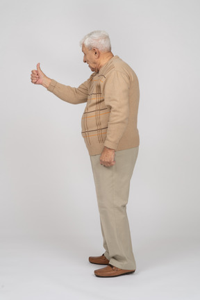 Vista lateral de um velho em roupas casuais, aparecendo o polegar