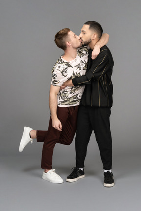 Two young men hugging lightly and kissing