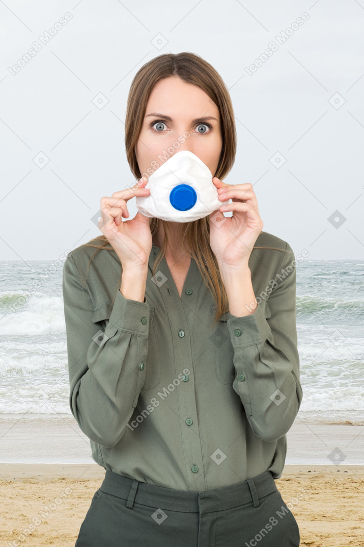 A surprised looking woman with a face mask at a beach
