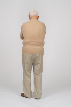 Vue arrière d'un vieil homme en vêtements décontractés debout avec les bras croisés
