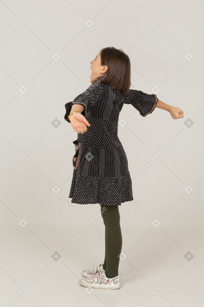 一个穿着裙子的小女孩的侧视图伸展她的背部和手臂