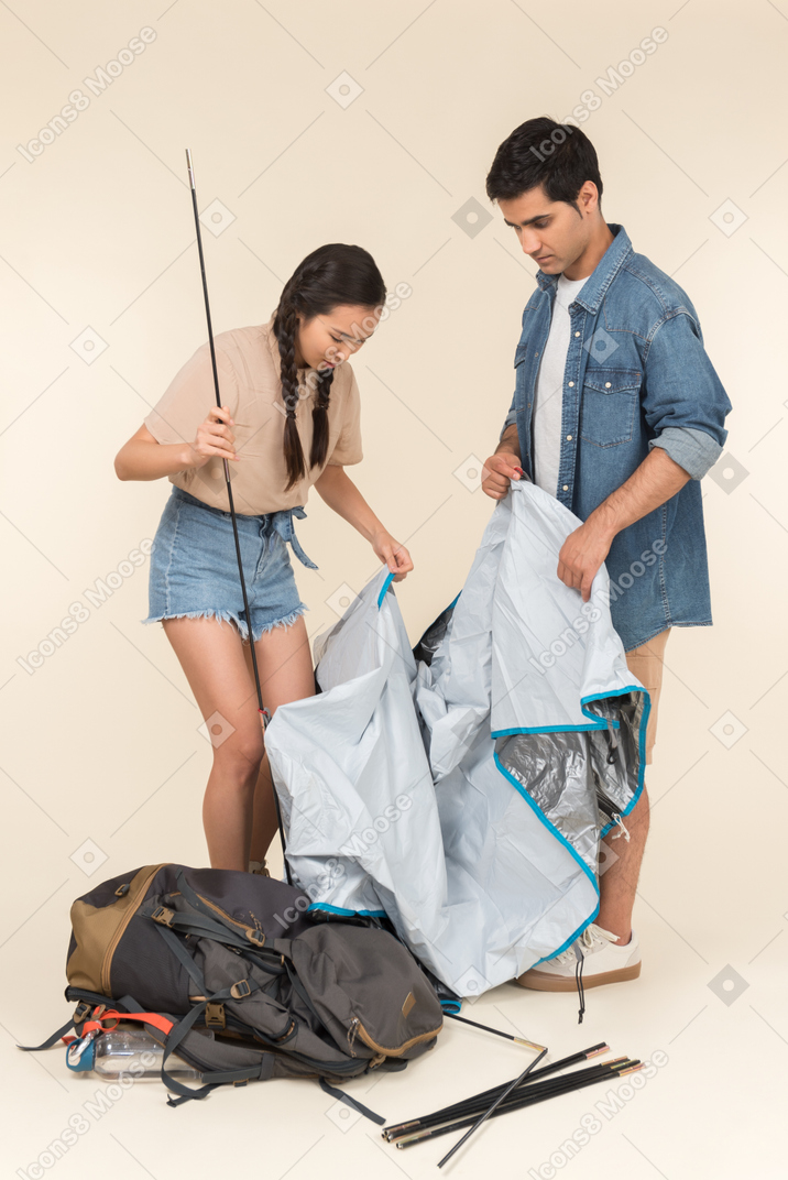 Young interracial couple building a tent