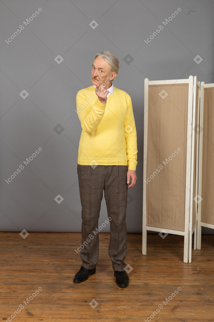Front view of an old man pointing finger while looking at camera